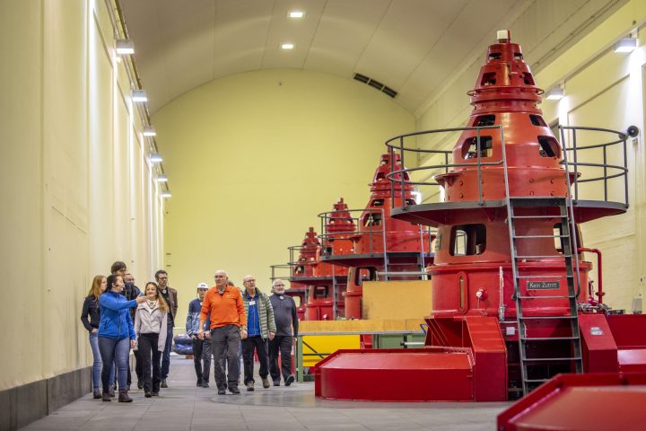 A group walks through the Innertkirchen 1 hydroelectric power station, which has 5 large turbines.